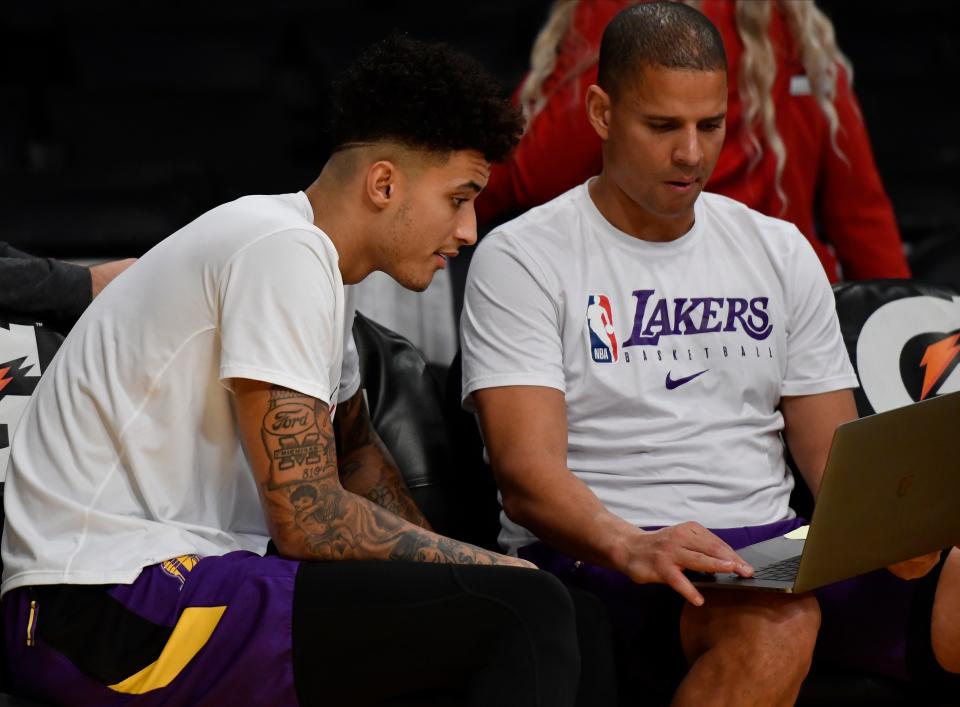 Los Angeles Lakers forward Kyle Kuzma (left) sits with assistant coach Miles Simon to look a video during pregame shoot around before playing the Sacramento Kings at Staples Center.