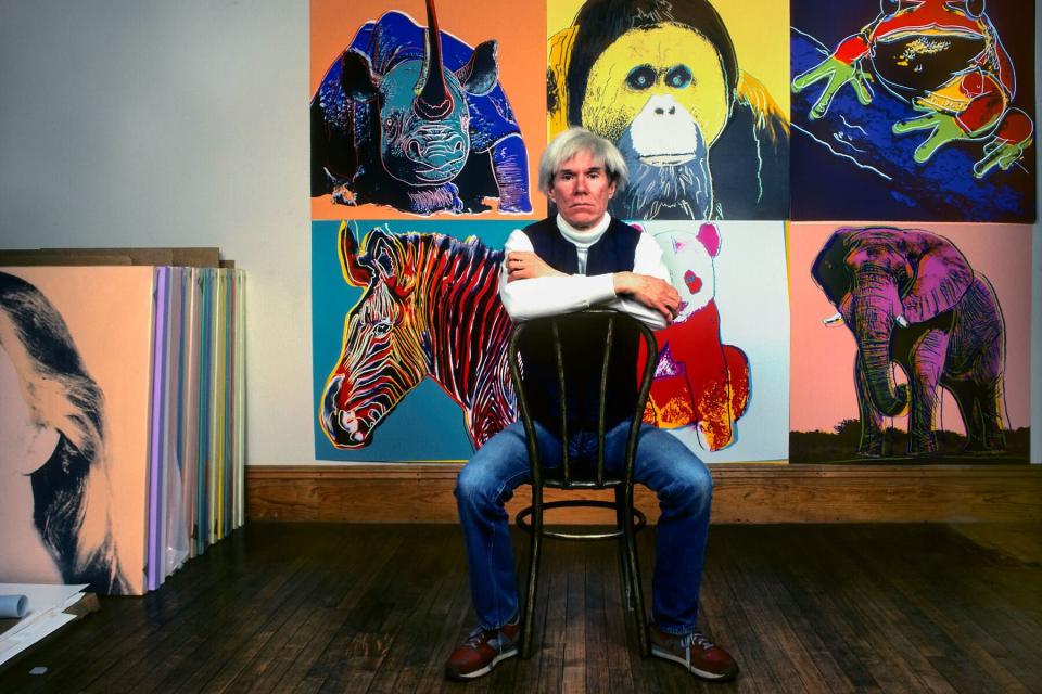 American Pop artist Andy Warhol sits in front of several paintings in his &#39;Endangered Species&#39; at his studio, the Factory, in Union Square, New York, New York, April 12, 1983.