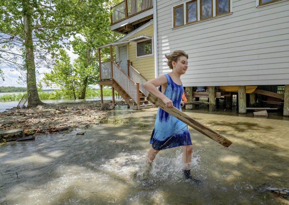 Tallulah Campbell, 8, clears out driftwood and other debris in preparation of Tropical Storm Barry near New Orleans, La., Thursday, July 11, 2019. The area is normally a driveway at her family's home that is one of the few on land called batture on the outside of the Mississippi River levee at the border of Orleans and Jefferson Parishes. (AP Photo/Matthew Hinton)