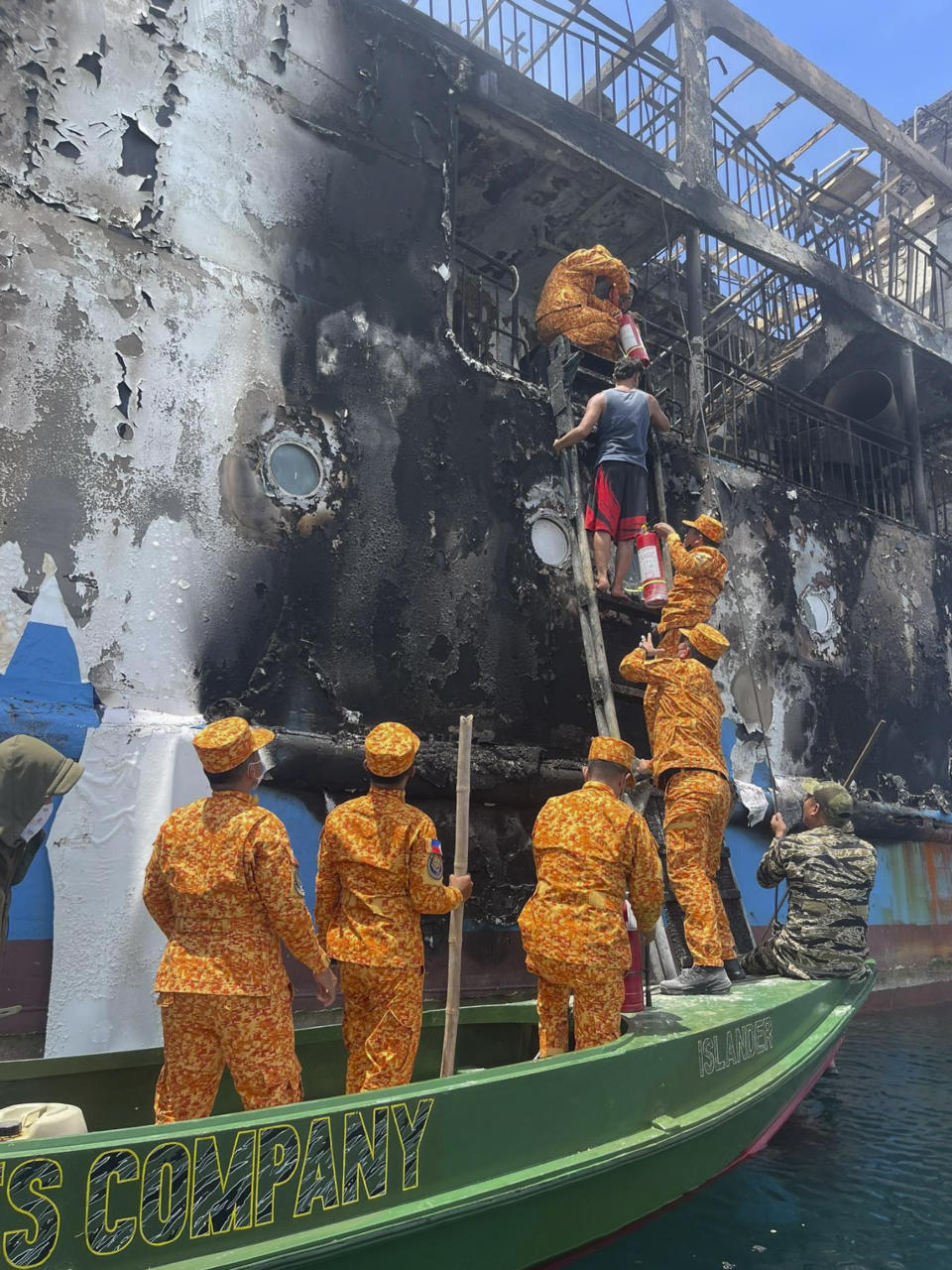 In this handout photo provided by the Philippine Coast Guard (PCG), PCG members check the remains of the MV Lady Mary Joy that caught fire in Basilan, southern Philippines early Thursday, March 30, 2023. More than a dozen people died while other were reported missing after an inter-island cargo and passenger ferry with about 200 passengers and crew onboard caught fire close to midnight in the southern Philippines, a provincial governor said Thursday. (Philippine Coast Guard via AP)