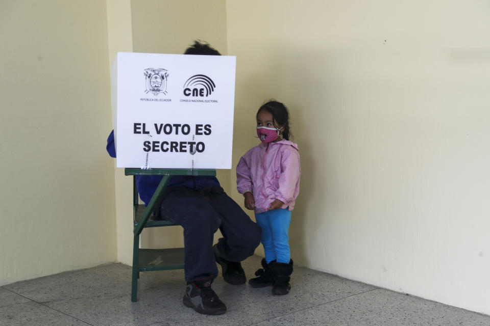 A voter, accompanied by his daughter, marks his ballot during a runoff presidential election in Quito, Ecuador, Sunday, April 11, 2021. Ecuadorians are voting, amid the COVID-19 pandemic, to choose between Andres Arauz, from the Union of Hope coalition, an economist protégé of former President Rafael Correa, and former banker Guillermo Lasso, of Creating Opportunities party, or CREO. (AP Photo/Dolores Ochoa)