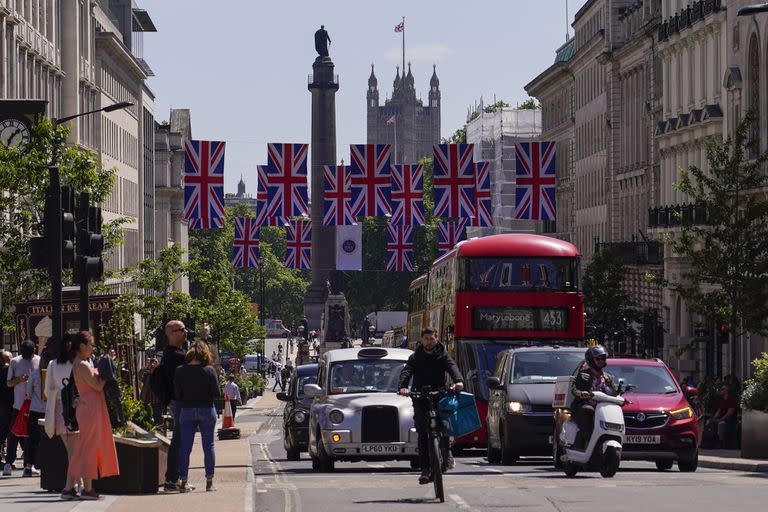 La gente cruza la calle en Piccadilly Circus mientras la calle está decorada con banderas de la Unión, en Londres, el viernes 27 de mayo de 2022