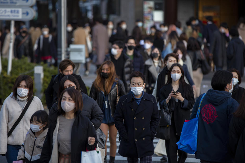 People wearing protective masks to help curb the spread of the coronavirus walk along a pedestrian crossing Sunday, Feb. 28, 2021, in Tokyo. Japan's second state of emergency set up to curb the coronavirus in Japan has been lifted in six urban areas this weekend and remain in the Tokyo area for another week until March 7. (AP Photo/Kiichiro Sato)