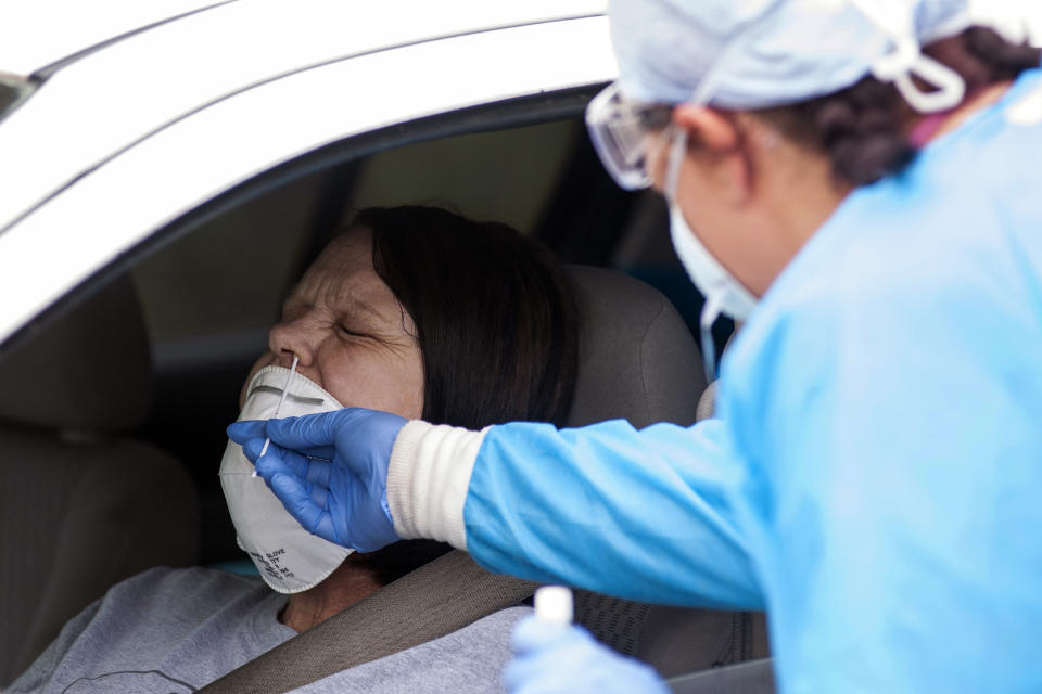 FILE - In this April 24, 2020, file photo, Regina Nelson, left, is tested for the coronavirus by Gina Johnson, a nurse tech, at the Bono Family Medical Clinic drive-thru testing site in Bono, Ark. Coronavirus cases are rising in nearly half the U.S. states, as states are rolling back lockdowns. (Quentin Winstine/The Jonesboro Sun via AP, File)