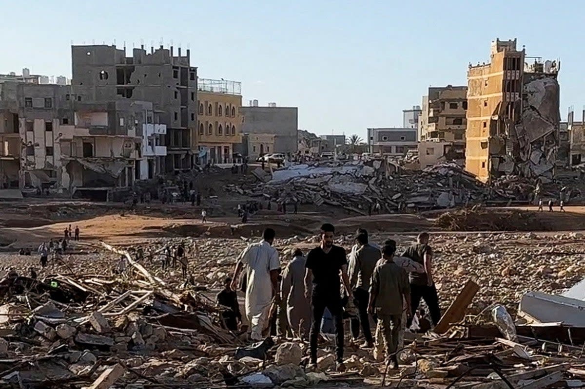 People walk through debris after a powerful storm and heavy rainfall hit Libya, in Derna, Libya, 12 September 2023 (Reuters)