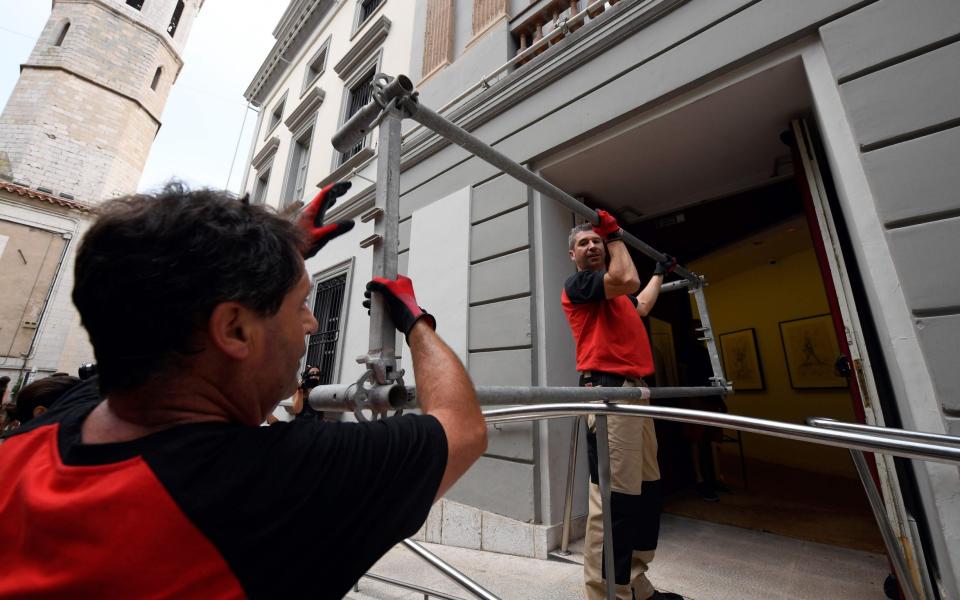 Two workers take scaffolding inside the Teatre-Museu Dali (Theatre-Museum Dali) before the exhumation  - Credit: LLUIS GENE/AFP