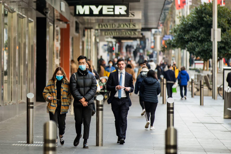 People wearing masks walk through Bourke Street Mall in Melbourne. 