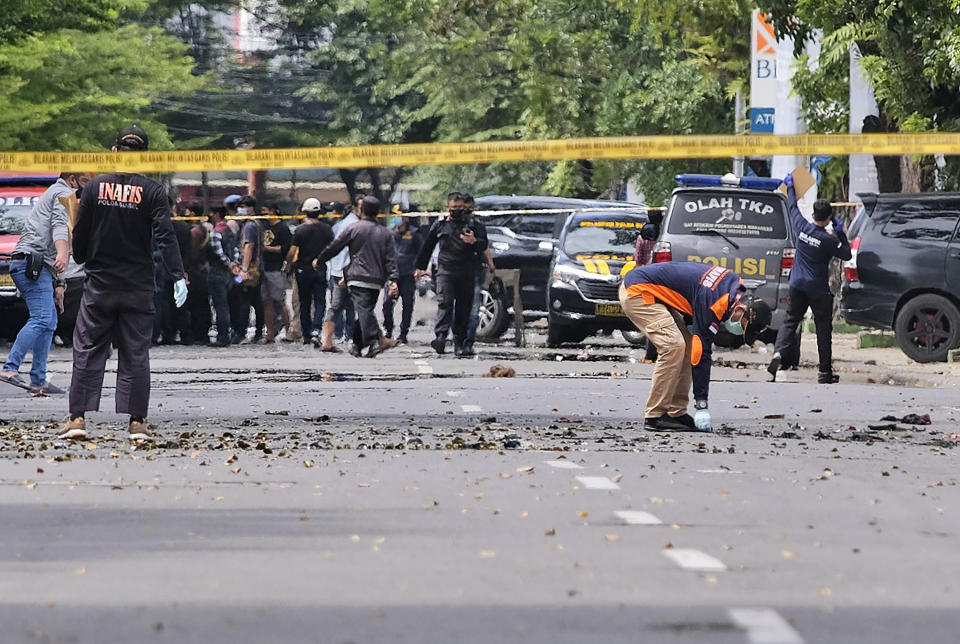 Police officers inspect the area near a church where an explosion went off in Makassar, South Sulawesi, Indonesia, Sunday, March 28, 2021. A suicide bomber blew himself up outside a packed Roman Catholic cathedral on Indonesia's Sulawesi island during a Palm Sunday Mass, wounding a number of people, police said. (AP Photo/Masyudi S. Firmansyah)