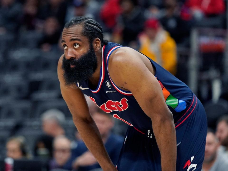 James Harden looks on while resting his hands on his knees during a game.