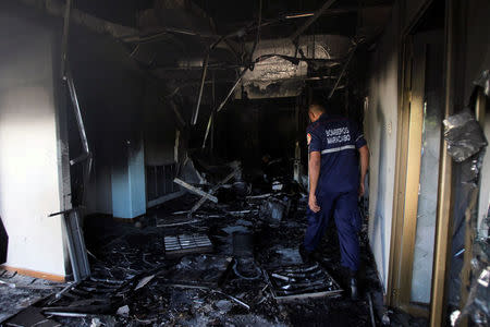 A firefighter walks past burned debris at the Ombudsman office in Maracaibo, Venezuela May 25, 2017. REUTERS/Isaac Urrutia