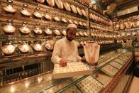 A shopkeeper arranges a box of earrings while showing to a customer (not pictured) at a gold shop, in Peshawar