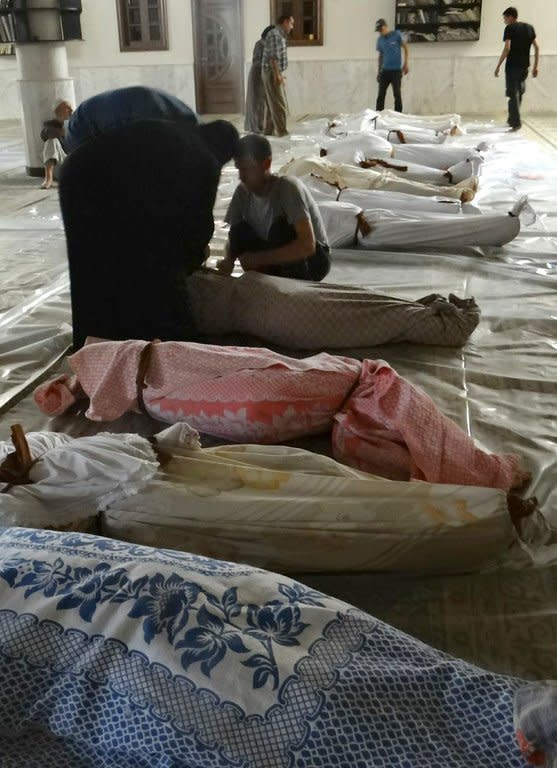 Syrians mourn among bodies wrapped in shrouds after what rebels claimed to be a toxic gas attack by government forces in eastern Ghouta, on the outskirts of Damascus, on August 21, 2013, in a photo released by the opposition's Shaam News Network. Syria on Thursday came under intense pressure to allow UN weapons inspectors to visit the site of an alleged chemical weapons attack near Damascus