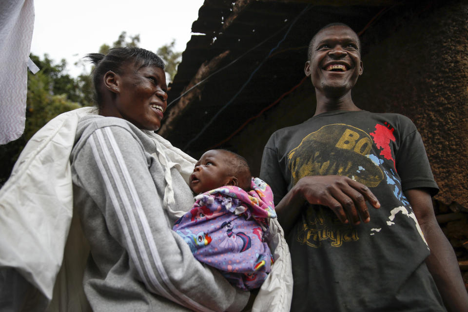 Mother Veronica Atieno, left, holds her daughter Shaniz Joy Juma, center, delivered a month earlier by a traditional birth attendant during a dusk-to-dawn curfew, accompanied by her husband Gabriel Owour Juma, right, in the Kibera slum of Nairobi, Kenya Friday, July 3, 2020. Kenya already had one of the worst maternal mortality rates in the world, and though data are not yet available on the effects of the curfew aimed at curbing the spread of the coronavirus, experts believe the number of women and babies who die in childbirth has increased significantly since it was imposed mid-March. (AP Photo/Brian Inganga)
