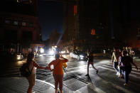 Pedestrians cross a dark street during a power outage, Saturday, July 13, 2019, in New York. (AP Photo/Michael Owens)