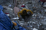 A man searches for people in a destroyed building in Adana, Turkey, Monday, Feb. 6, 2023. A powerful quake has knocked down multiple buildings in southeast Turkey and Syria and many casualties are feared. (AP Photo/Khalil Hamra)