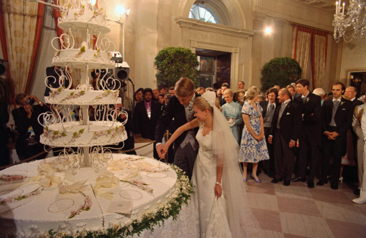 Washington, DC.: At the wedding of Edward Finch Cox and Tricia Nixon, the bride and groom cut the wedding cake as guests look on.