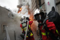 Firefighters pull off a fire on burning truck during a demonstration in Paris, Thursday, Dec. 5, 2019. Small groups of protesters are smashing store windows, setting fires and hurling flares in eastern Paris amid mass strikes over the government's retirement reform. (AP Photo/Thibault Camus)