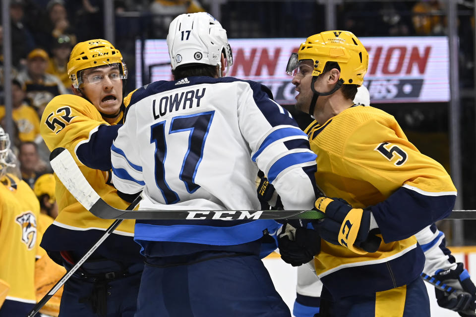 Nashville Predators' Cal Foote (52) and Kevin Gravel (5) scuffle with Winnipeg Jets center Adam Lowry (17) during the first period of an NHL hockey game Saturday, March 18, 2023, in Nashville, Tenn. (AP Photo/Mark Zaleski)