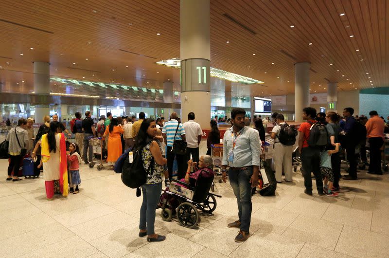 FILE PHOTO: Passengers wait for their luggage at a conveyor be at the Chhatrapati Shivaji International airport in Mumbai