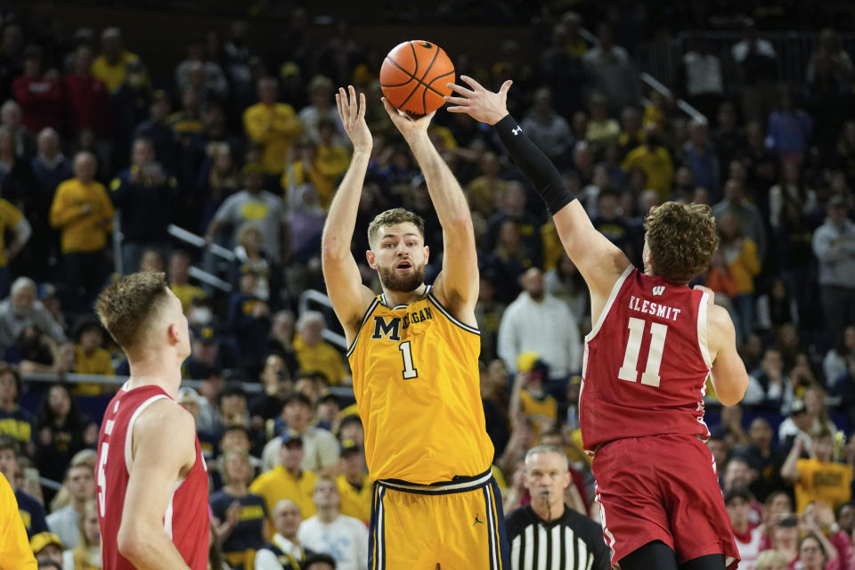 Michigan center Hunter Dickinson (1) hits a three-point basket as Wisconsin guard Max Klesmit (11) defends in the second half as time expires to send the game to overtime in an NCAA college basketball game in Ann Arbor, Mich., Sunday, Feb. 26, 2023. (AP Photo/Paul Sancya)