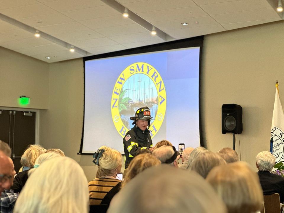 New Smyrna Beach Mayor Fred Cleveland, dressed in a firefighter uniform and carrying a bucket filled with candy, makes his entrance at the New Smyrna Beach State of the City address in the Brannon Center, Monday, Feb. 26, 2024.