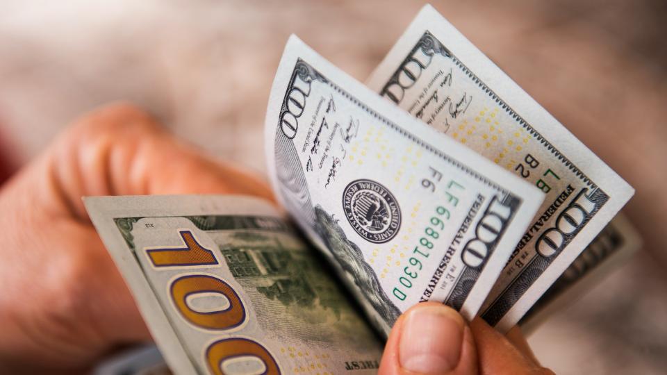 High angle view of unrecognizable person counting US Dollar bills.