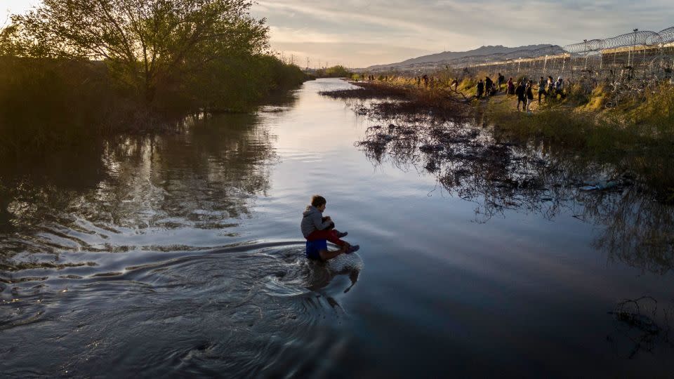 Immigrants wade through the Rio Grande while crossing from Mexico into El Paso, Texas, on March 12, 2024. - John Moore/Getty Images