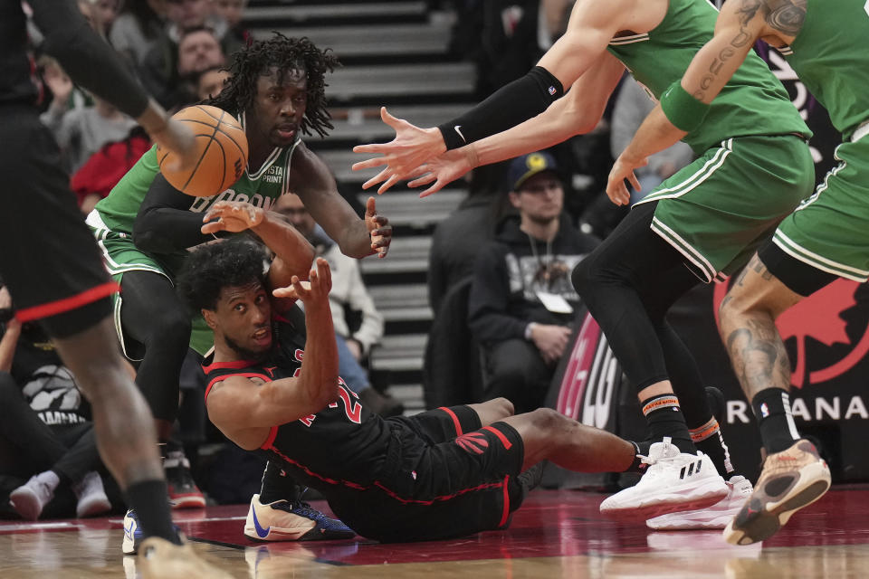 Toronto Raptors forward Thaddeus Young , bottom, tries to make a pass from the floor as Boston Celtics guard Jrue Holiday, back left, defends during second-half NBA basketball game action in Toronto, Monday Jan. 15, 2024. (Nathan Denette/The Canadian Press via AP)