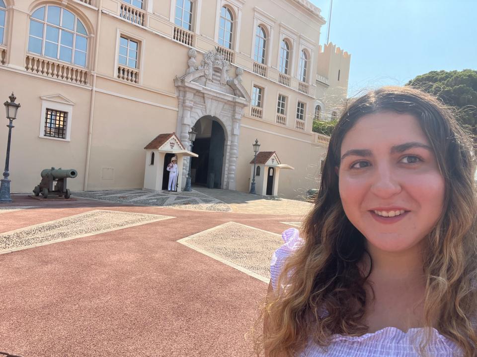 A woman taking a selfie in front of a palace with guards.