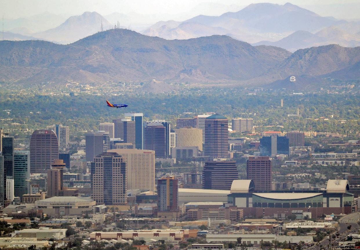 In this Tuesday, July 24, 2018 photo, a jet comes in for approach over downtown, in Phoenix as temperatures exceed 100 degrees in the morning hours.