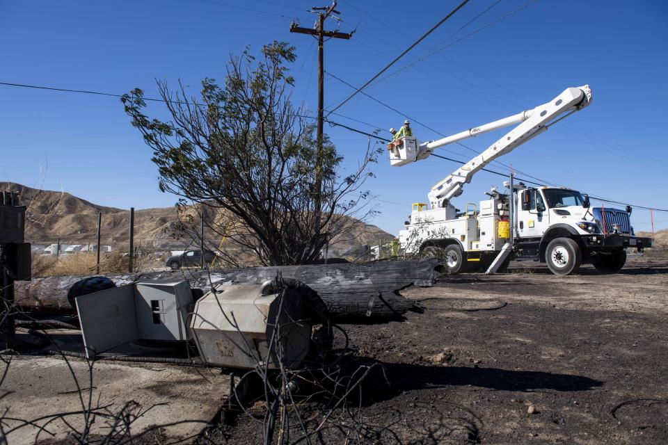 SoCal Edison workers replace power lines that were damaged from the Tick Fire, Thursday, Oct. 25, 2019, in Santa Clarita, Calif. An estimated 50,000 people were under evacuation orders in the Santa Clarita area north of Los Angeles as hot, dry Santa Ana winds howling at up to 50 mph (80 kph) drove the flames into neighborhoods (AP Photo/ Christian Monterrosa)