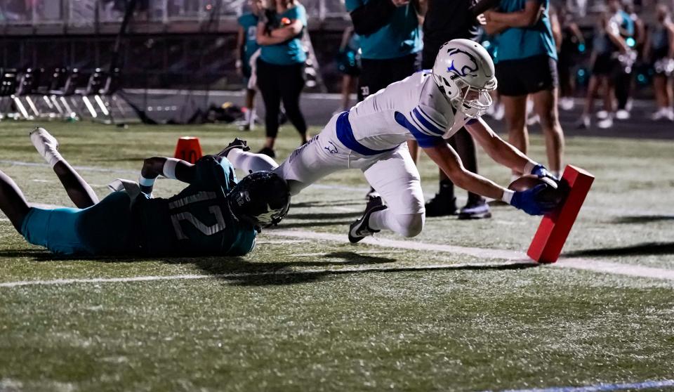 Barron Collier Cougars receiver Brody Graham (1) dives for the pylon to score a touchdown as Gulf Coast Sharks defender Zechariah Joly (12) dives for him during the second quarter of the Catfish Bowl at Gulf Coast High School in Naples on Friday, Nov. 3, 2023.