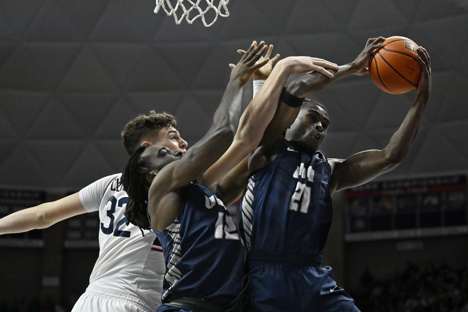New Hampshire forward Clarence Daniels (21) grabs a rebound against UConn center Donovan Clingan (32) as New Hampshire forward Promise Opurum defends in the first half of an NCAA college basketball game, Monday, Nov. 27, 2023, in Storrs, Conn. (AP Photo/Jessica Hill)