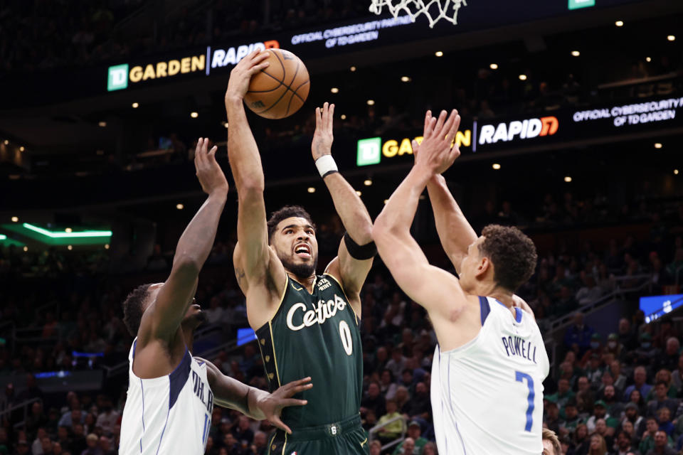 Boston Celtics forward Jayson Tatum (0) drives to the basket between Dallas Mavericks forward Dorian Finney-Smith, left, and center Dwight Powell (7) during the first half of an NBA basketball game, Wednesday, Nov. 23, 2022, in Boston. (AP Photo/Mary Schwalm)