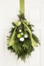 <p>Your door decoration doesn't have to be a wreath, you know. Bundled together with floral wire and fragrant greenery — yew, holly, spruce and eucalyptus — this swag makes a grand entrance. Choose a color scheme so your ornaments and ribbon can match. </p>