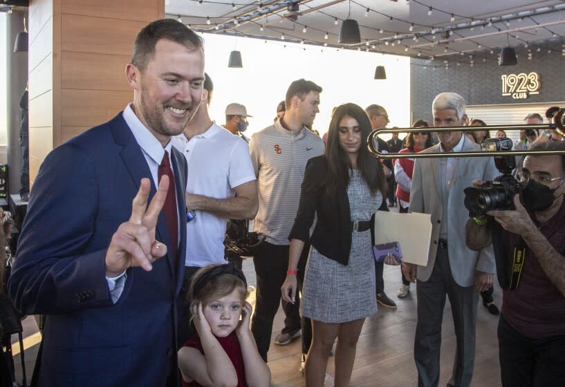 LOS ANGELES, CA - November 29 2021: Lincoln Riley flashes Trojan sign as his youngest daughter Stella, 5, plugs her ears as Trojan band plays after he was announced as the new head football coach at USC during a press conference at the Coliseum on Monday, Nov. 29, 2021 in Los Angeles, CA. (Brian van der Brug / Los Angeles Times