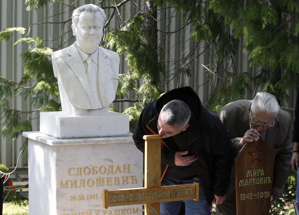 People pay last respect to Mirjana Markovic, right, the widow of former strongman Slobodan Milosevic, cross on left, during her funeral at the yard of his estate in his home town of Pozarevac, Serbia, Saturday, April 20, 2019. Markovic died last week in Russia where she had been granted asylum. The ex-Serbian first lady had fled there in 2003 after Milosevic was ousted from power in a popular revolt and handed over to the tribunal in The Hague, Netherlands. (AP Photo/Darko Vojinovic)