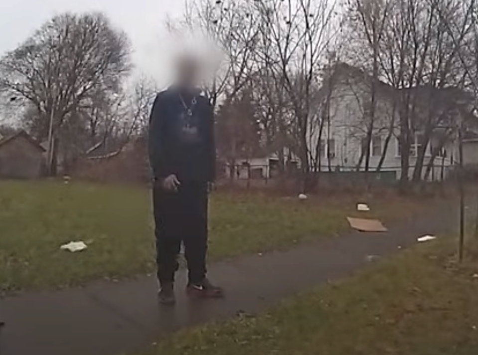 Todd Novick, stands on Murray Street near Lyell Avenue on Christmas Eve 2023, answering questions from a police officer. Police shot him in the back as he ran away from this sidewalk after they say he pulled a BB gun from his pocket.