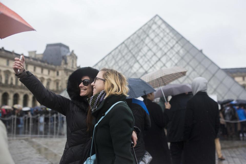 Two women take a selfie, as they wait to enter the re-opened Louvre museum, a day after a man attacked French soldiers near the museum in Paris, Saturday, Feb. 4, 2017. The Louvre in Paris reopened to the public Saturday morning, less than 24-hours after a machete-wielding assailant shouting "Allahu Akbar!" was shot by soldiers, in what officials described as a suspected terror attack. (AP Photo/Kamil Zihnioglu)