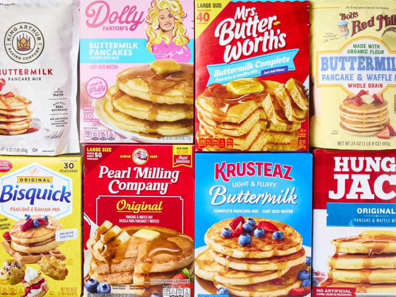 overhead shot of all of the pancake mixes being tested. From left to right: King Arthur, Dolly Parton, Mrs.Butterworth's. Bob's Red Mill, Bisquick, Pearl Milling Company, KRusteaz, Hungry JAck