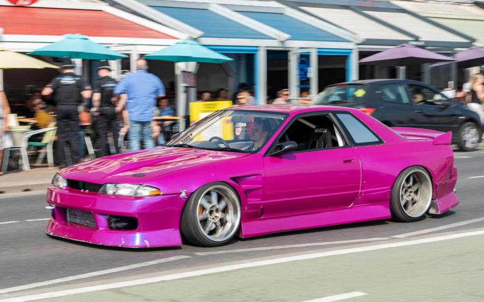 Magenta custom car driving past arches restaurants along Western Esplanade, Southend on Sea, Essex, UK. - Alamy