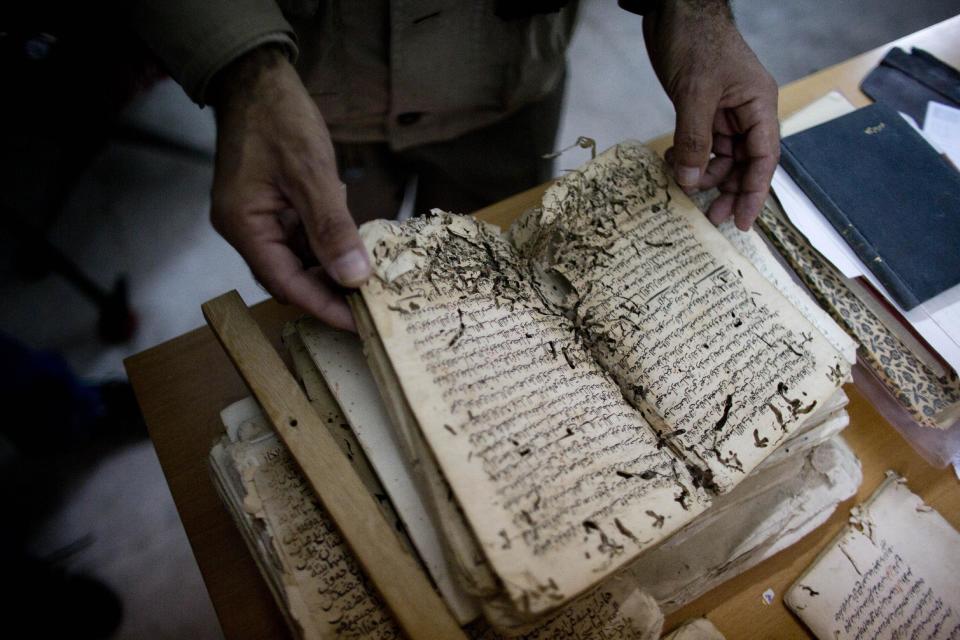 In this photo taken on Monday, Jan. 27, 2014, an employee shows an old manuscript at the al-Aqsa mosque compound library in Jerusalem. The library has a collection of some 4,000 old manuscripts with about a quarter considered in poor condition. Half of the books are already undergoing restoration funded by the Waqf, Jordan’s Islamic authority which manages the holy site, and with assistance from UNESCO. (AP Photo/Dusan Vranic)