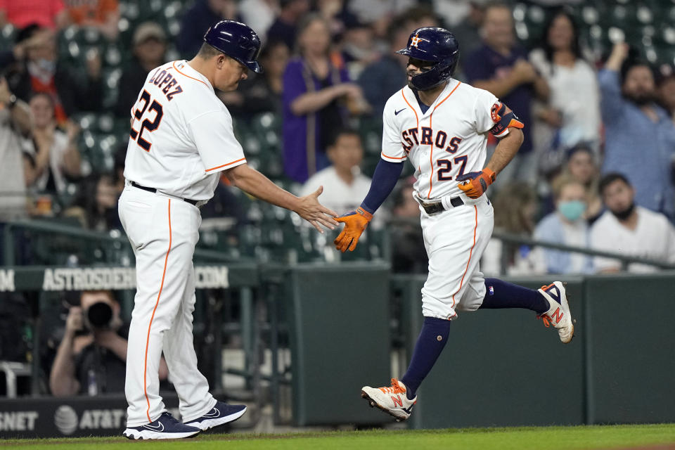 Houston Astros' Jose Altuve (27) is congratulated by first base coach Omar Lopez (22) after hitting a home run against the Los Angeles Angels during the first inning of a baseball game Wednesday, May 12, 2021, in Houston. (AP Photo/David J. Phillip)