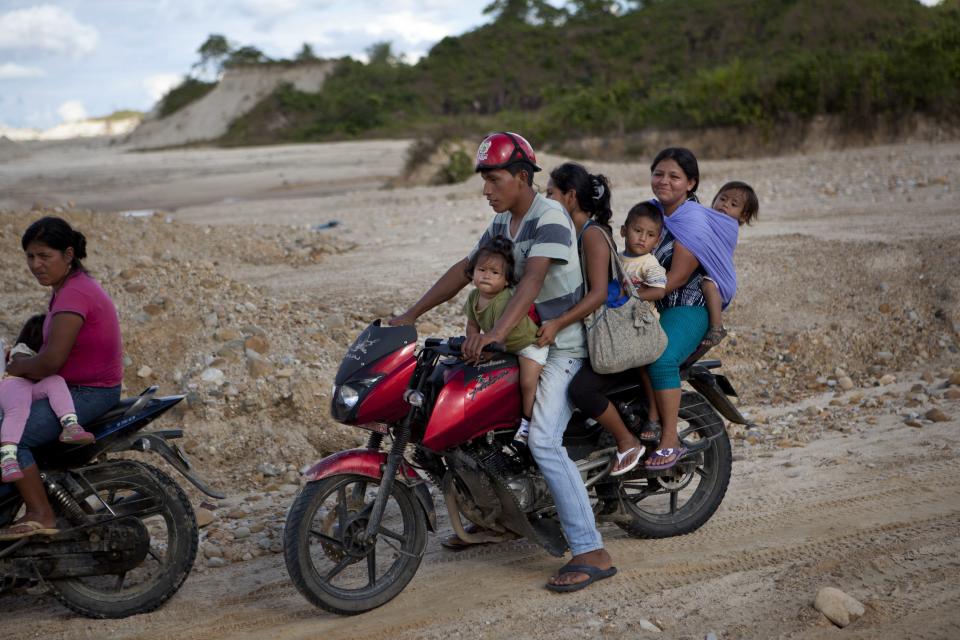 A man carries his family away from an illegal mining camp on his motorcycle, near the area where machinery for illegal mining is being destroyed by policemen in Huepetuhe district in Peru's Madre de Dios region in Peru, Monday, April 28, 2014. Some 1,500 soldiers, police and marines have begun destroying illegal gold mining machinery in Peru’s southeastern jungle region of Madre de Dios. Illegal mining accounts for about 20 percent of Peru's gold exports, but most miners are poor migrants from the Andean highlands. (AP Photo/Rodrigo Abd)