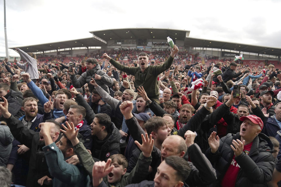 Wrexham fans invade the pitch celebrating promotion to League One after the final whistle of a League Two soccer match, Saturday, April 13, 2024, in Wrexham, Wales. The Welsh team co-owned by actor Ryan Reynolds clinched promotion to the third tier of English soccer thanks to a 6-0 home win over Forest Green on Saturday. (Jacob King/PA via AP)