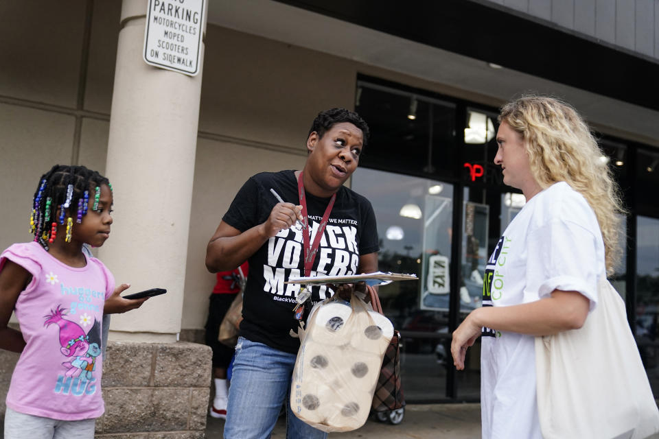 Canvasser Sienna Giraldi, 26, right, talks to Atlanta resident Makela Atchison, center, Thursday, July 20, 2023, in Atlanta. Activists with the Stop Cop City Vote Coalition are trying to get the signatures of more than 70,000 Atlanta residents by Aug. 14 to force a referendum allowing voters to decide the fate of a proposed police and firefighter training center. (AP Photo/Brynn Anderson)