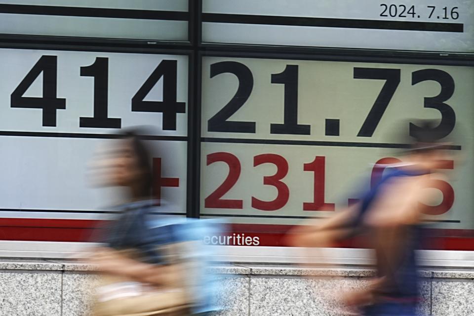 People walk in front of an electronic stock board showing Japan's Nikkei index at a securities firm Tuesday, July 16, 2024, in Tokyo. (AP Photo/Eugene Hoshiko)