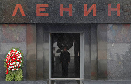 FILE PHOTO: An honour guard is seen though the rain drops during a wreath-laying ceremony, held by supporters of the Russian Communist Party, at Vladimir Lenin's mausoleum on the eve of the 95th anniversary of the 1917 Bolshevik revolution in Red Square in Moscow, November 6, 2012. The sign reads "Lenin". REUTERS/Maxim Shemetov/File Photo