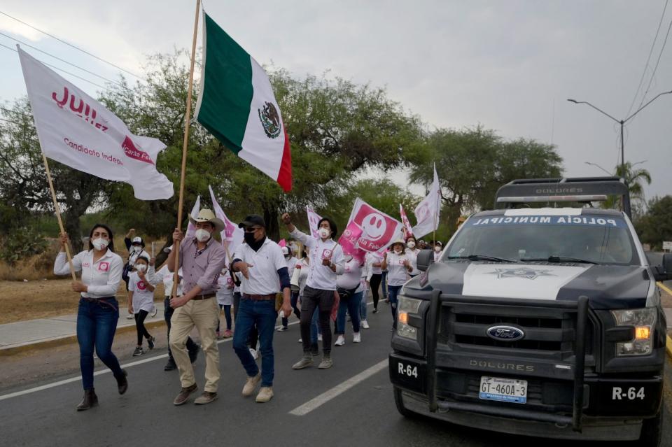 Campaign supporters march in the street with flags