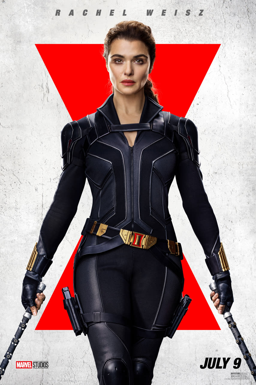 Rachel Weisz wears a black suit and sports staff weapons in each hand.